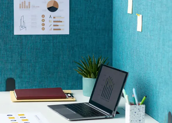 Desk with a laptop against a teal wall